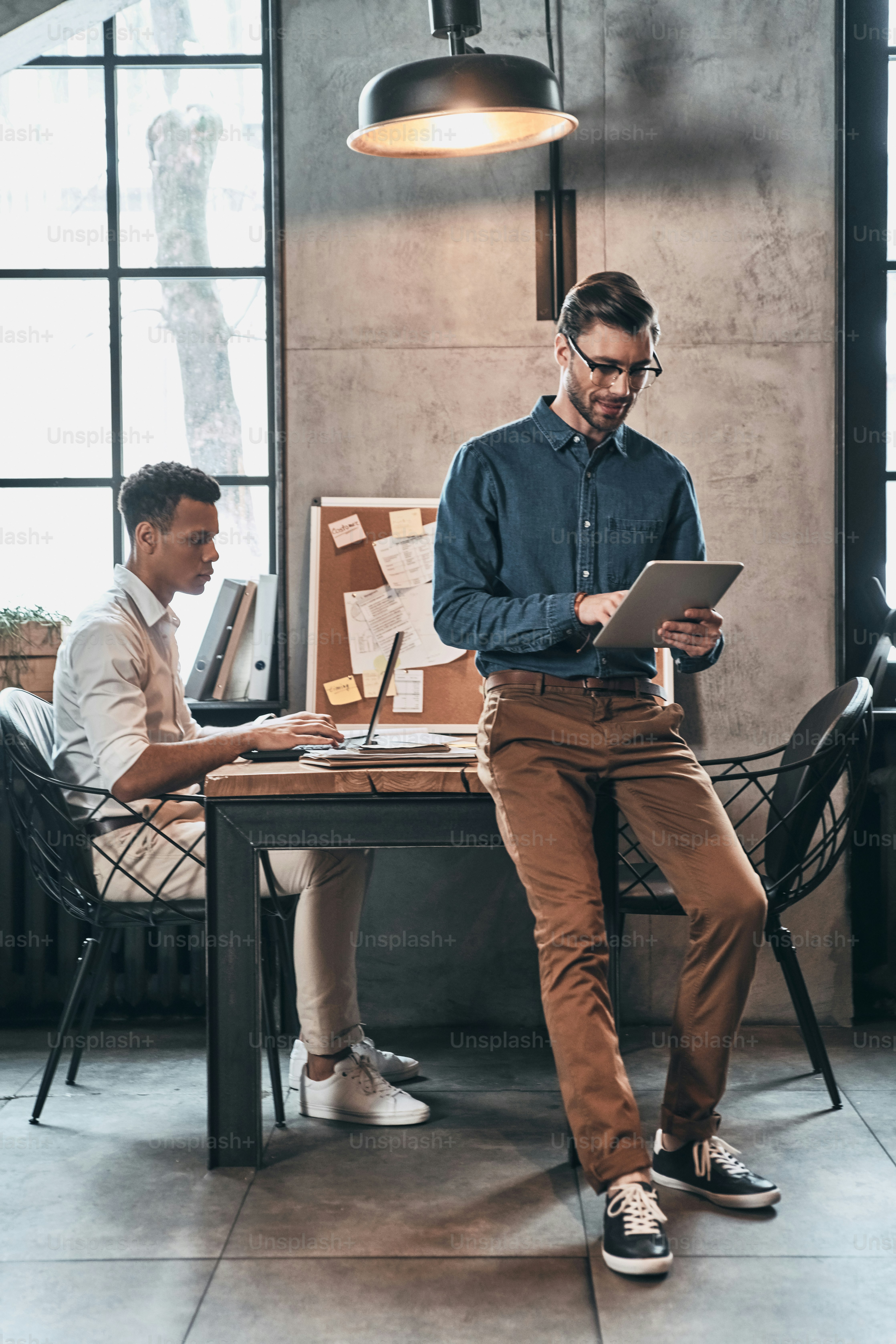 Two confident men in smart casual wear concentrating at work while ...