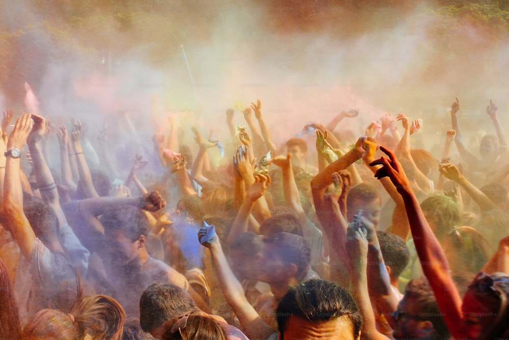 happy people crowd partying under colorful powder cloud