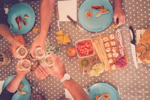 alternative point of view of people having lunch or dinner at home. aged seniors two couple on the table drinking wine and eating food. colors and dots