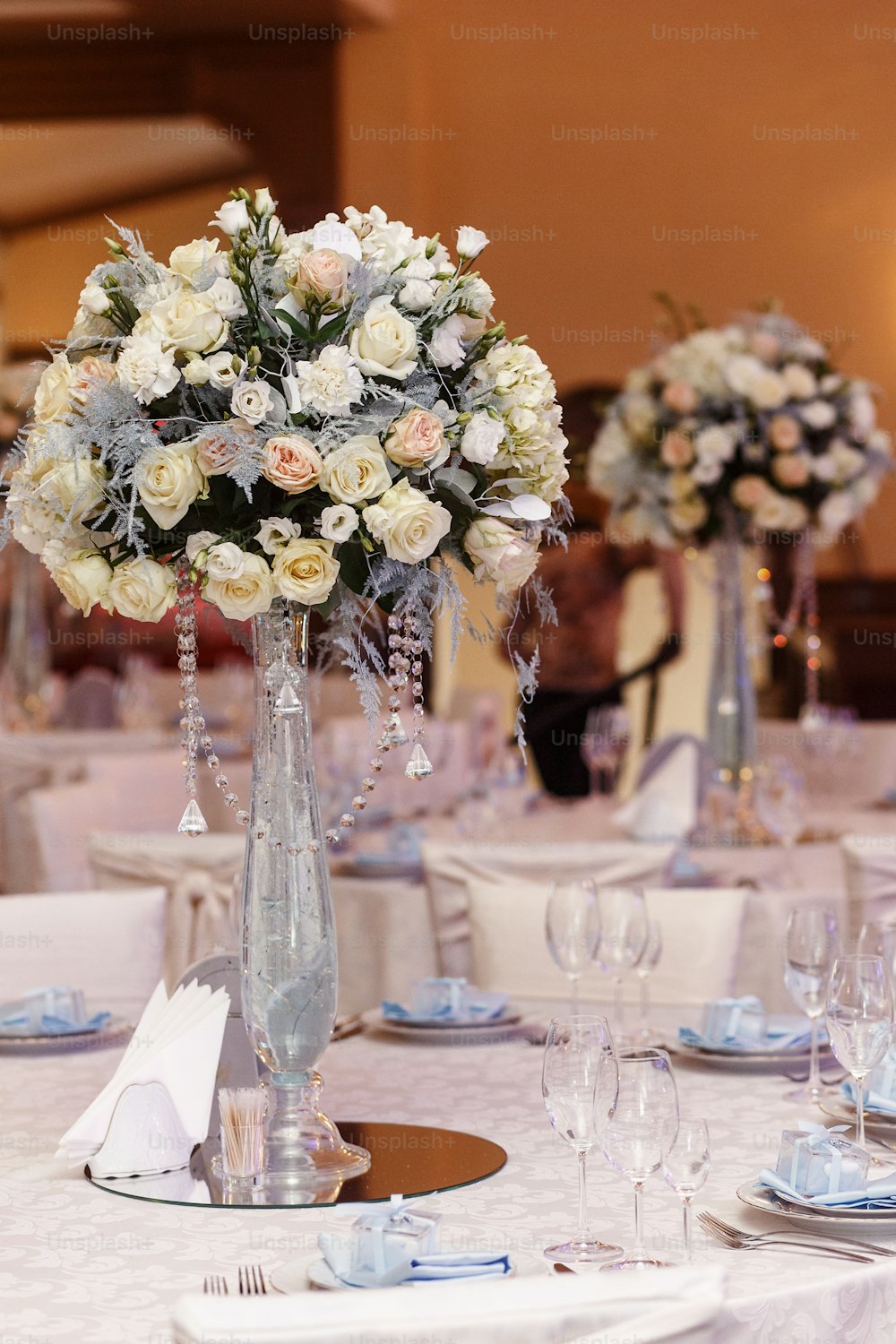 luxury wedding decor with flowers and glass vases with jewels on round tables. arrangements of decorations at wedding reception. expensive catering. space for text