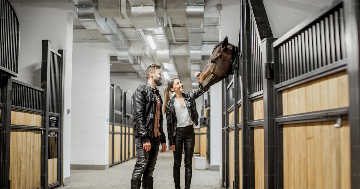Young couple riders in leather jackets standing with horse in the ...