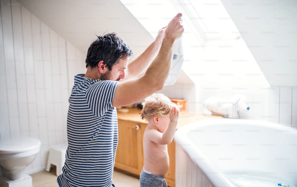 Vater mit einem Kleinkind zu Hause, bereitet sich auf ein Bad vor. Vaterschaftsurlaub.