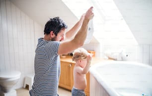 Father with a toddler boy at home, getting ready for a bath. Paternity leave.