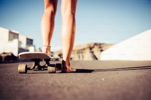 美しい白人の足と裸の足は、太陽の下で町の屋外や自然の場所の路上でスケートボードを開始して移動する準備ができています