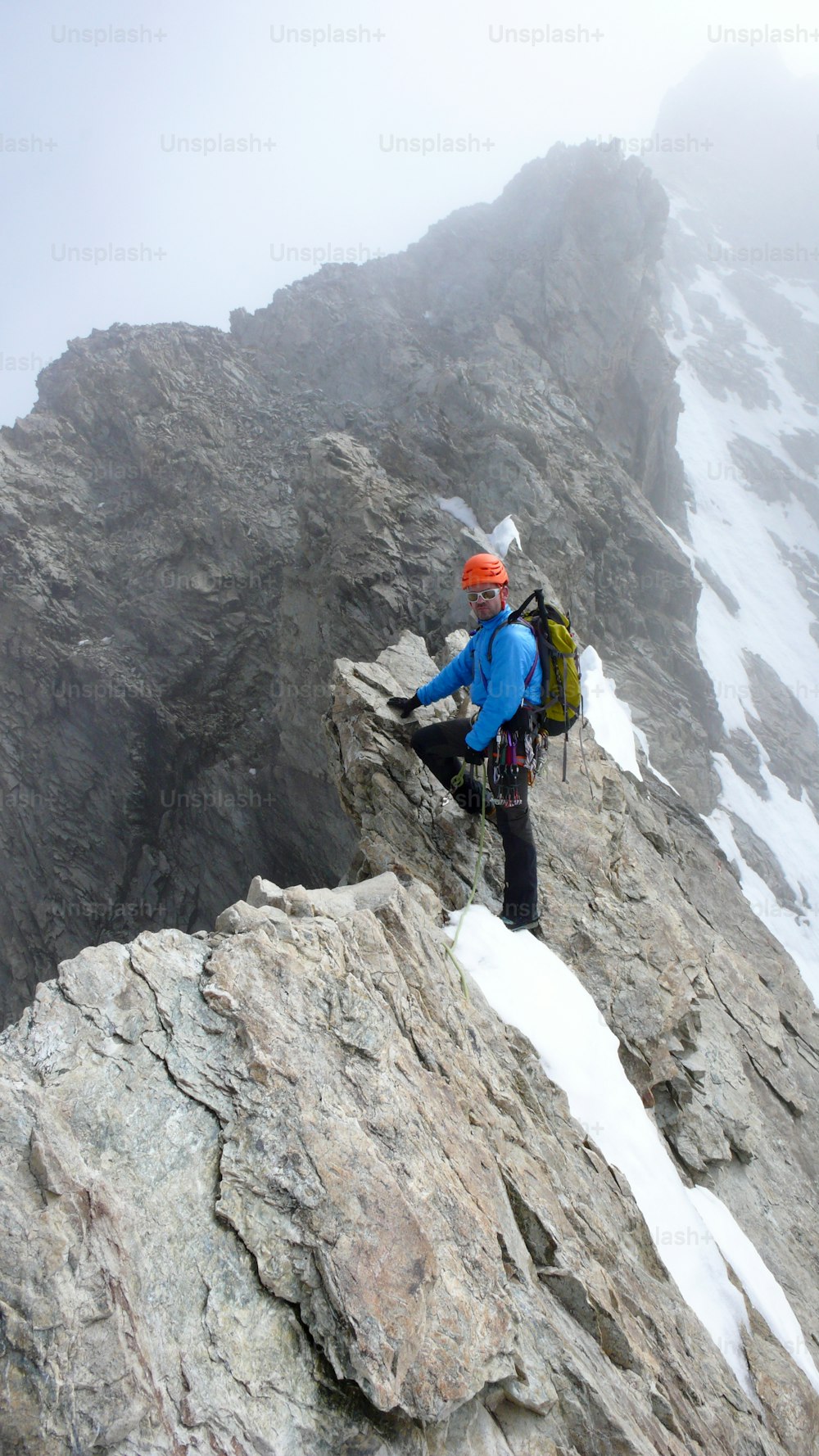 Ein männlicher Bergführer führt beim Klettern auf einem exponierten Granitgrat in den Alpen