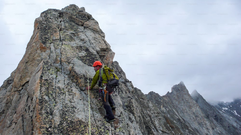 A male mountain guide lead climbing on an exposed granite ridge in the Alps