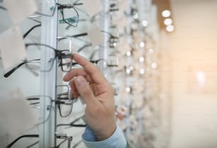 Close up male hand putting eyeglasses in optician store. Eye care concept