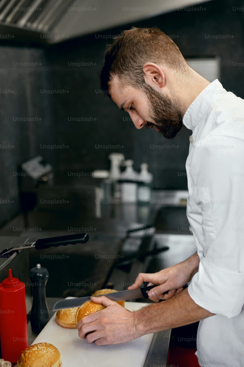 Chef Cooking Burgers In Restaurant Kitchen, Cutting Buns. High Resolution.