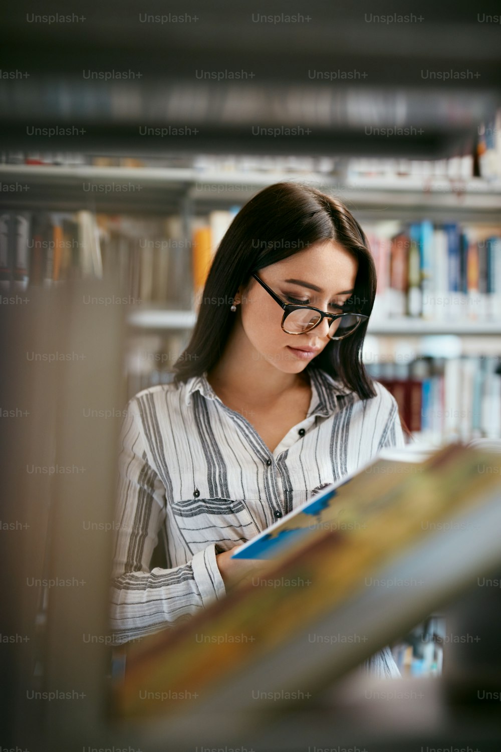 Mujer Estudiante Buscando Libros En La Librería O Biblioteca. Mujer Buscando Libro De Texto En Las Estanterías. Alta resolución