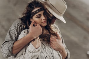 Handsome cowboy man in white hat touching cheek of beautiful boho gypsy woman with leather headband, face closeup portrait