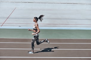 屋外で運動しながらジョギングするスポーツウェアを着た若い女性の全身トップビュー