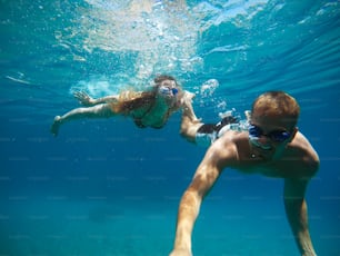 Fröhliches Paar, das Spaß unter Wasser hat und Selfies macht.