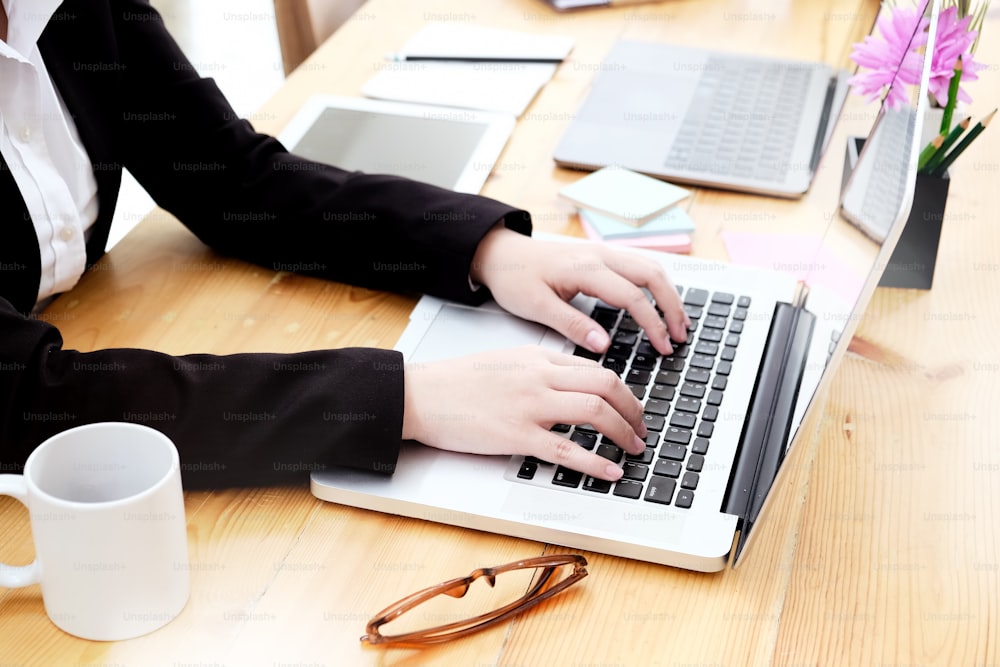 Businesswoman using laptop at office desk.