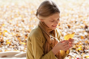 a young girl holding a leaf in her hands