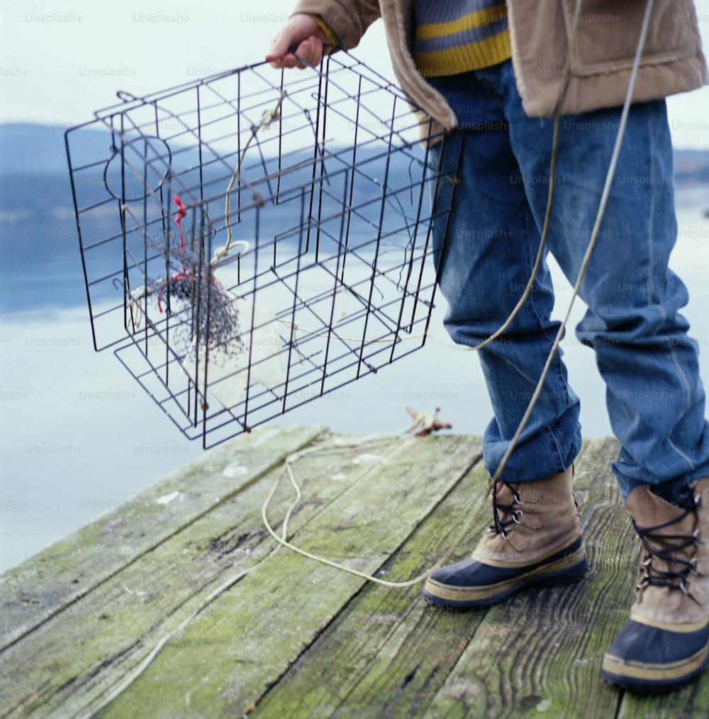 a person standing on a dock holding a wire basket