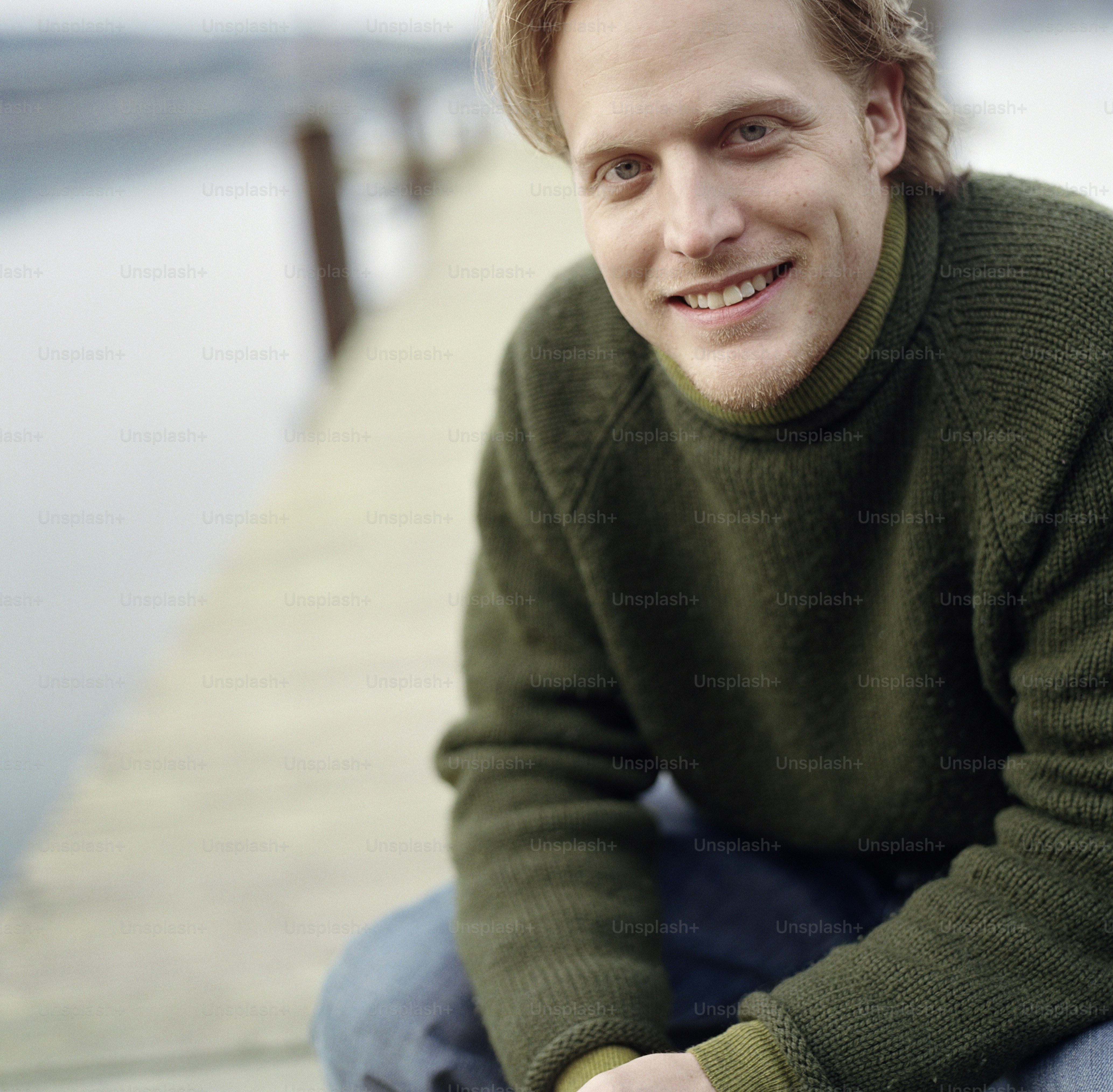 a man sitting on a dock smiling at the camera