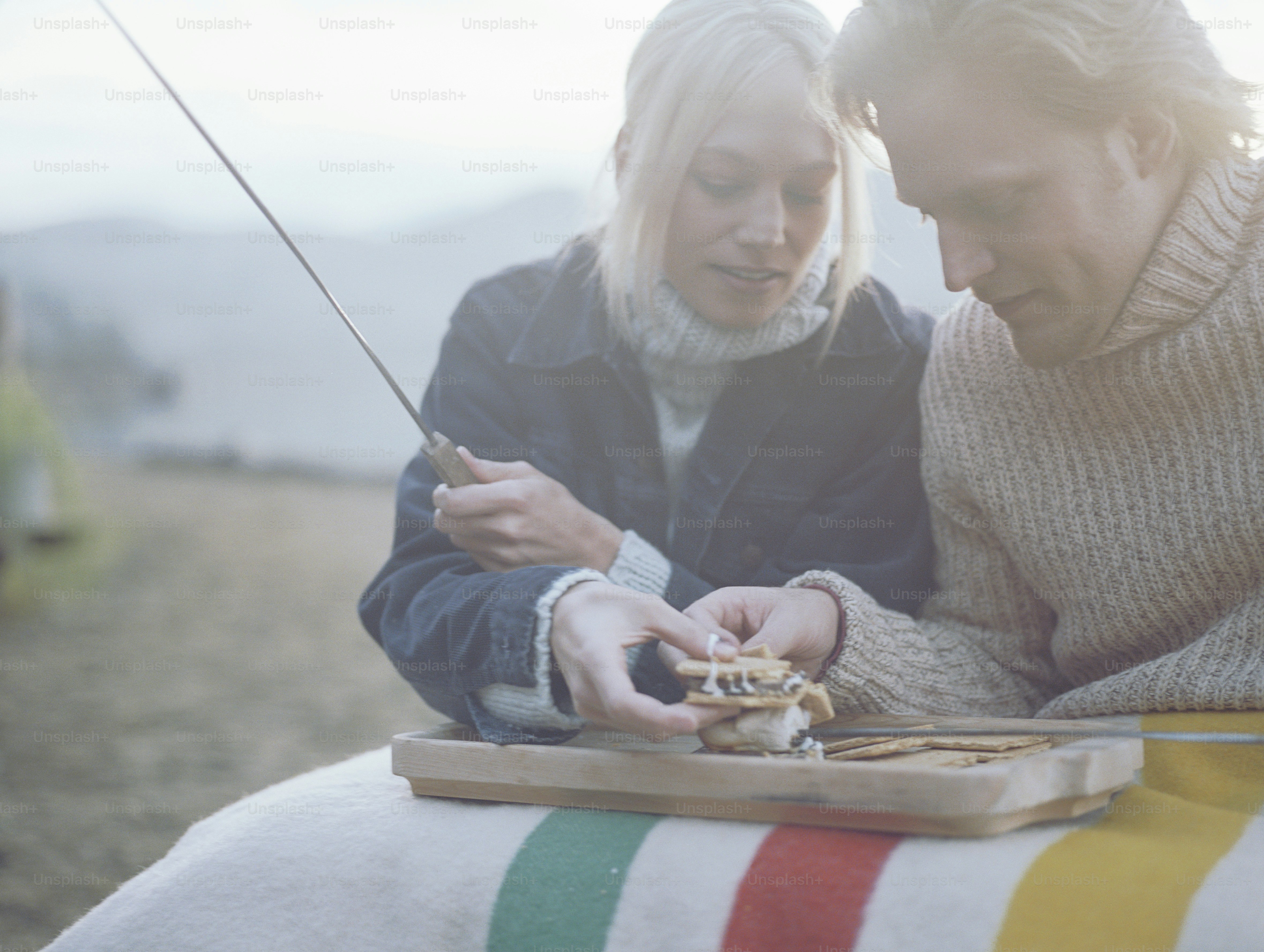 a man and a woman sitting on a bench looking at a cell phone