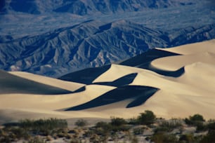 Una vista de una cadena montañosa desde la cima de una duna de arena