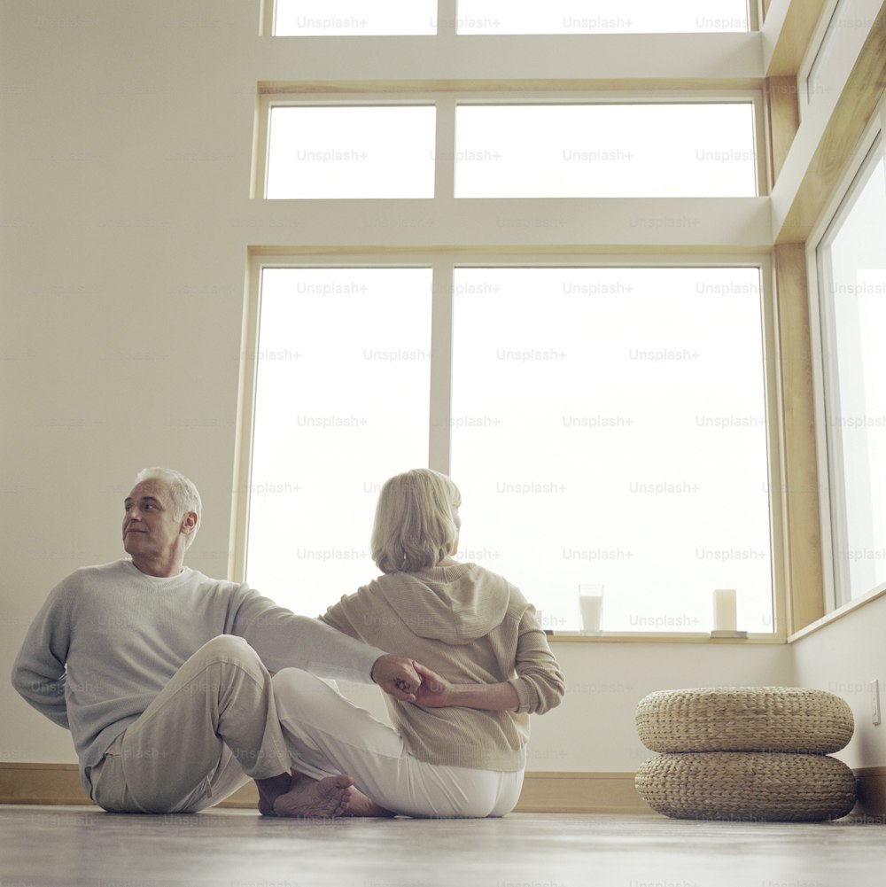 a man and woman sitting on the floor in front of a window
