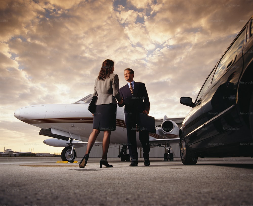 a man and a woman standing in front of a private jet