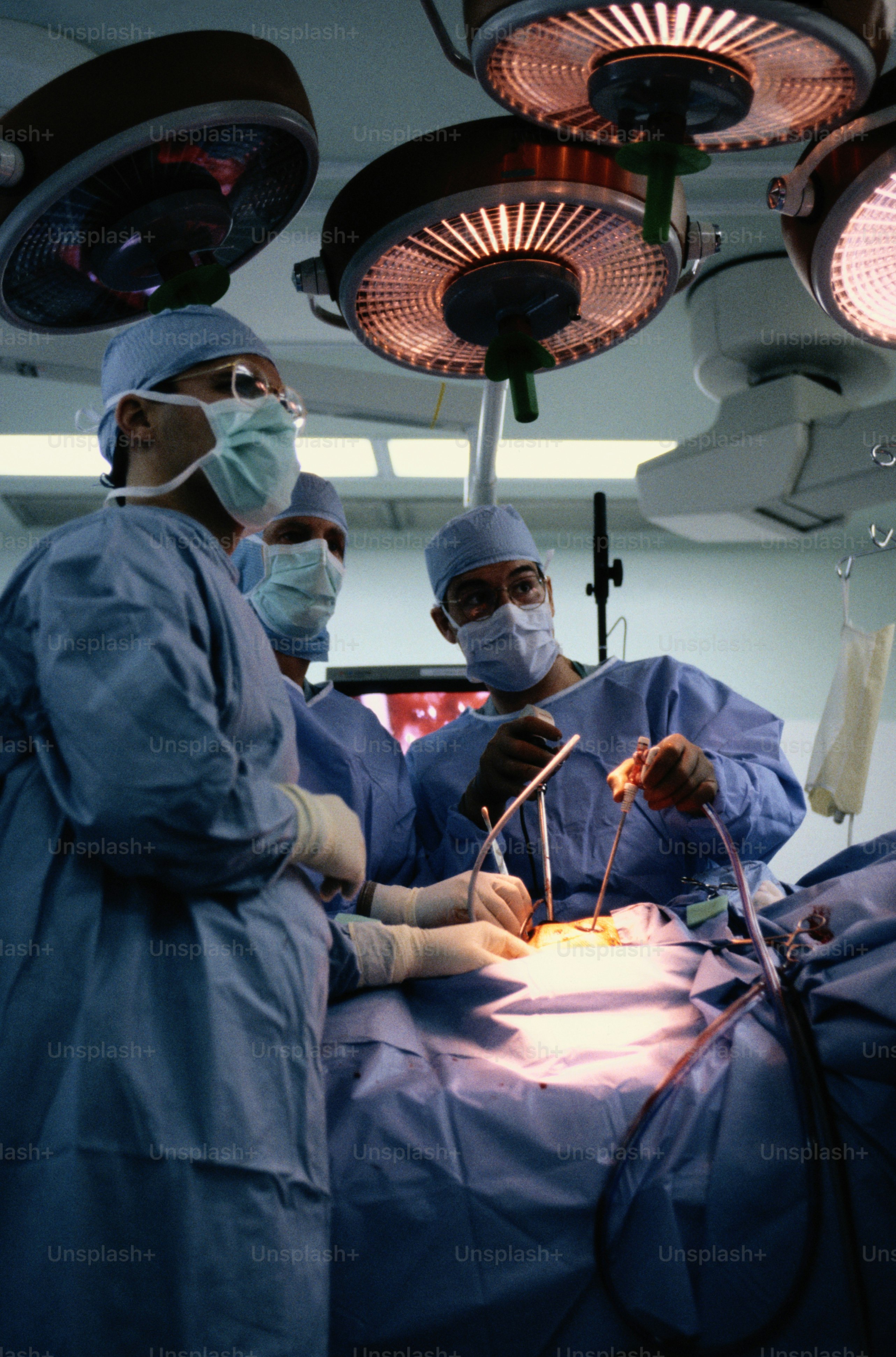 A group of doctors performing surgery on a patient photo – Three people ...