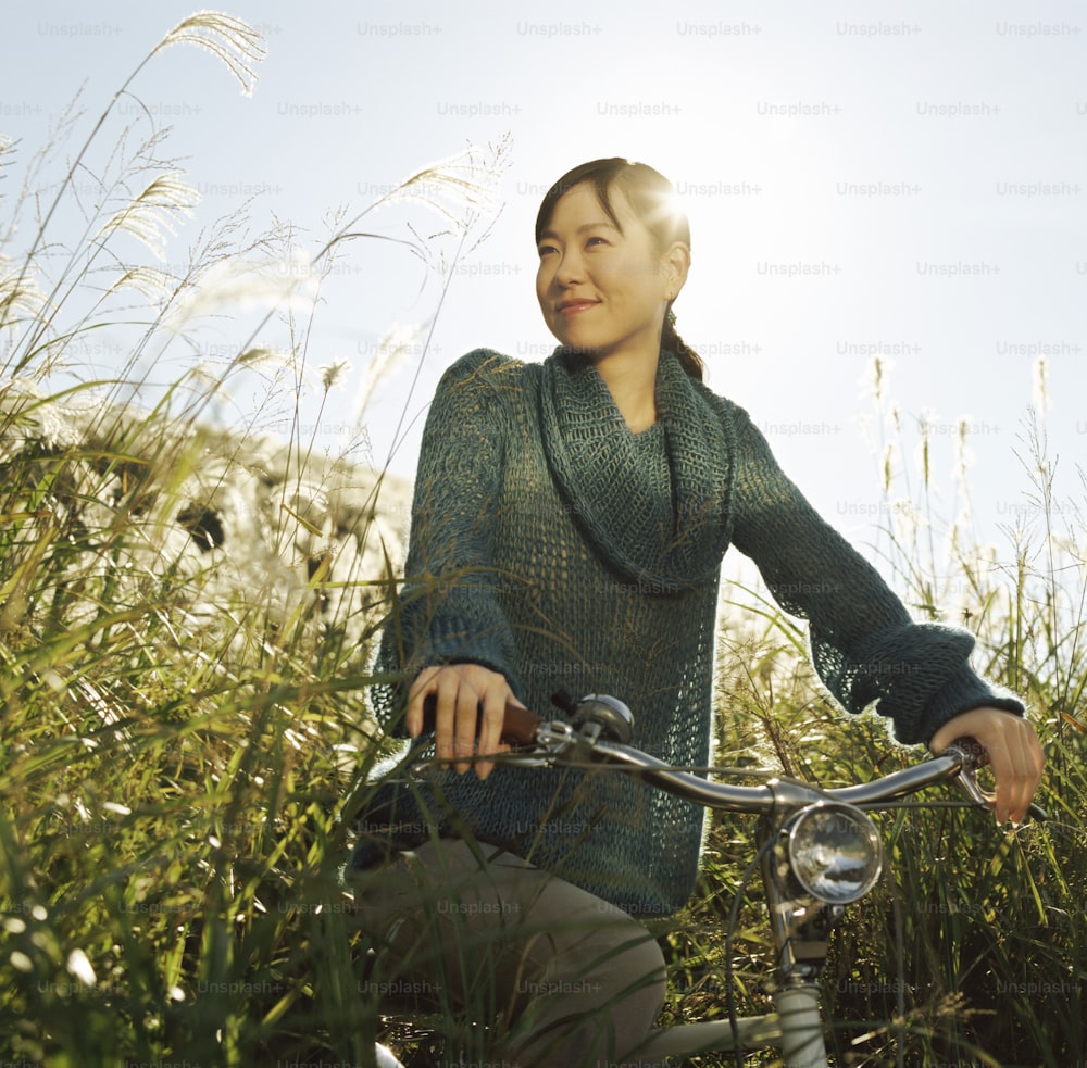 a woman riding a bike through tall grass