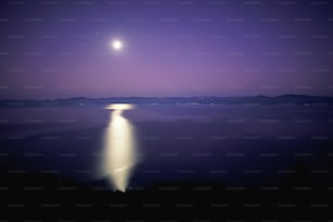 a full moon is seen over a body of water