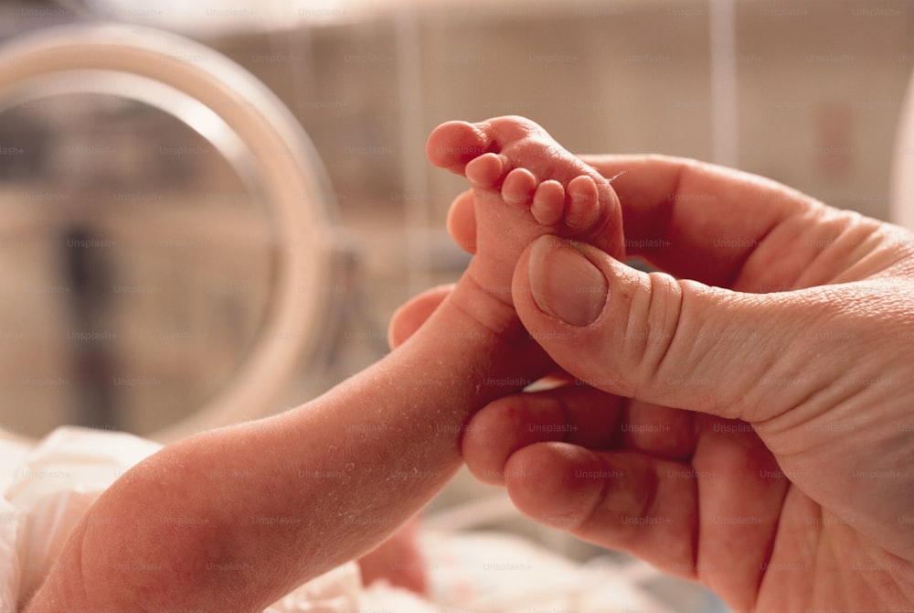 um close up de uma pessoa segurando o pé de um bebê