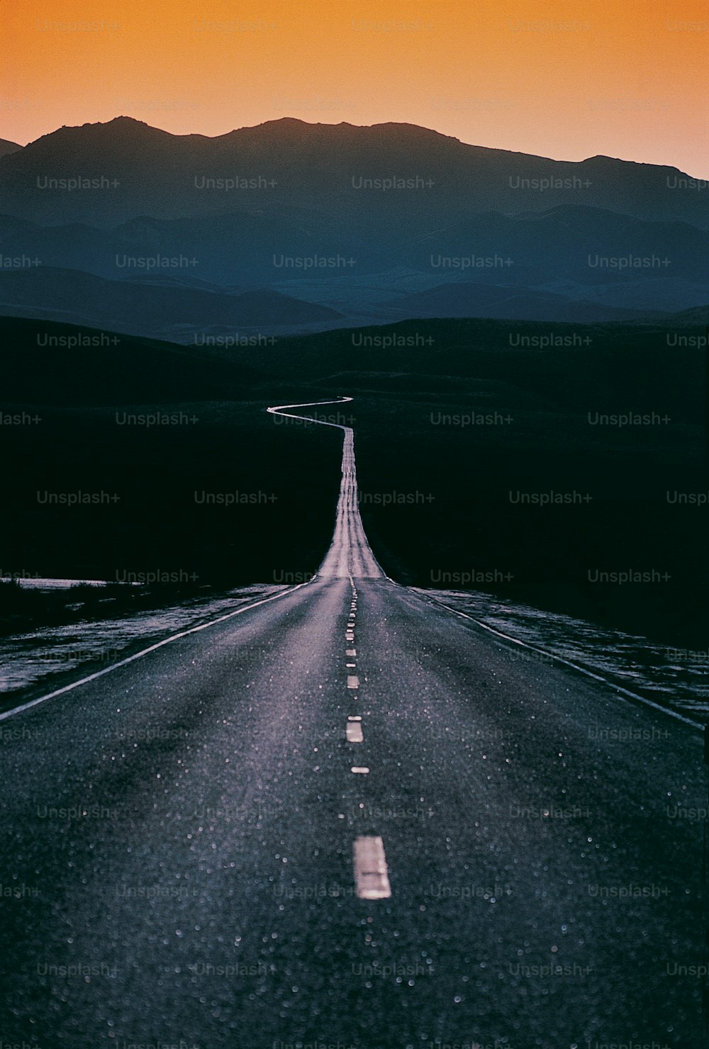 an empty road with mountains in the background