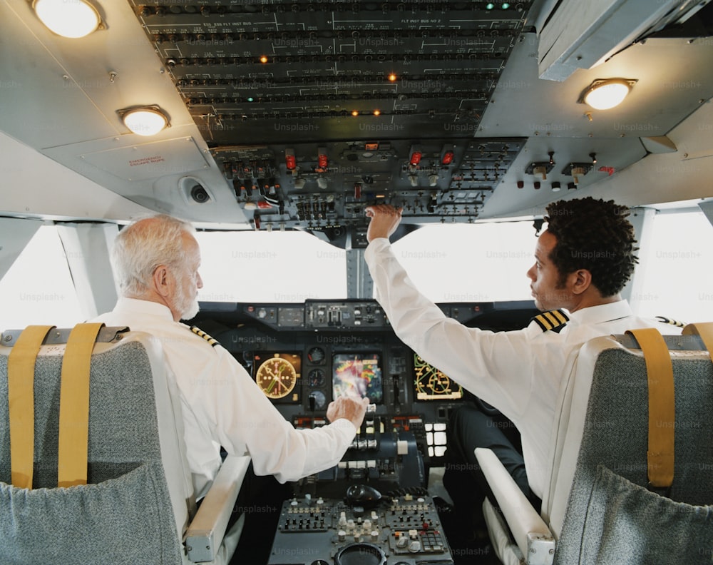 a couple of men sitting in the cockpit of a plane