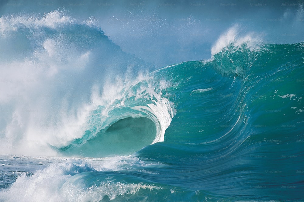 a large wave crashing into the ocean on a sunny day