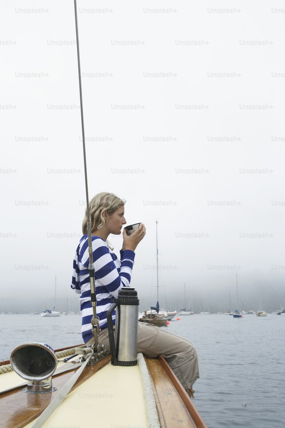 a woman sitting on a sailboat taking a picture with her cell phone