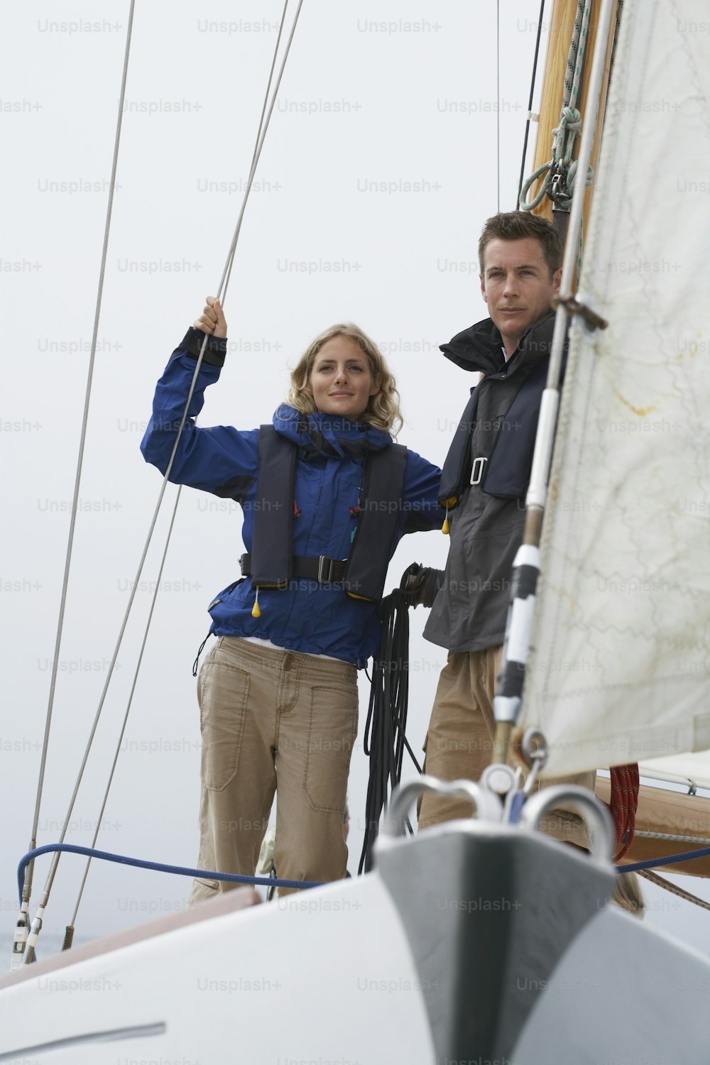 a man and a woman standing on a sailboat