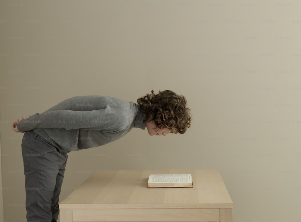 a person bending over a table with a book on it