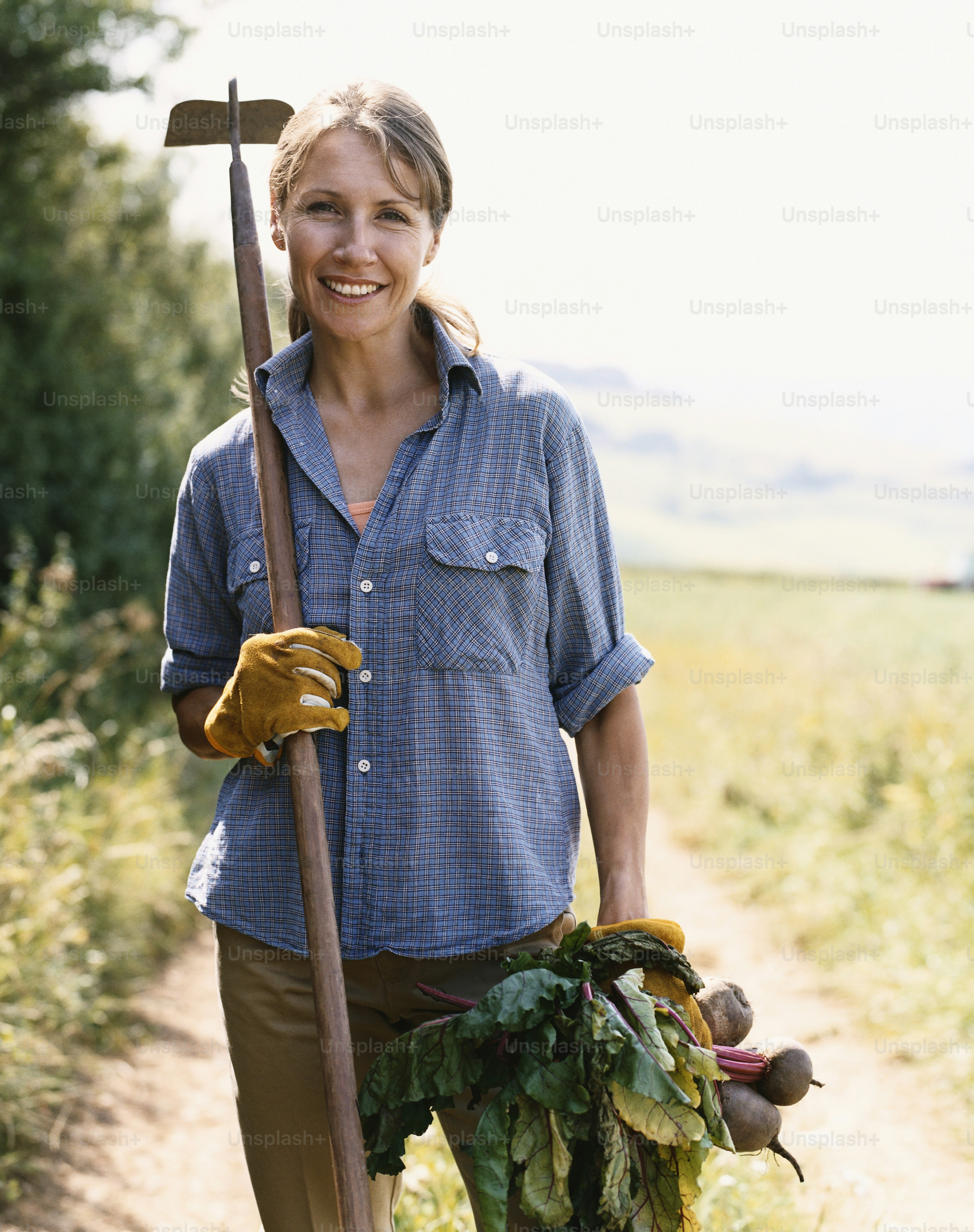 A woman holding a shovel and a bunch of vegetables photo – Farm Image ...