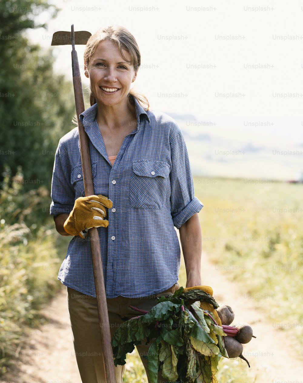 uma mulher segurando uma pá e um monte de legumes