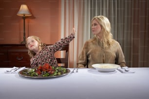 uma mulher e uma criança sentadas em uma mesa com um prato de comida