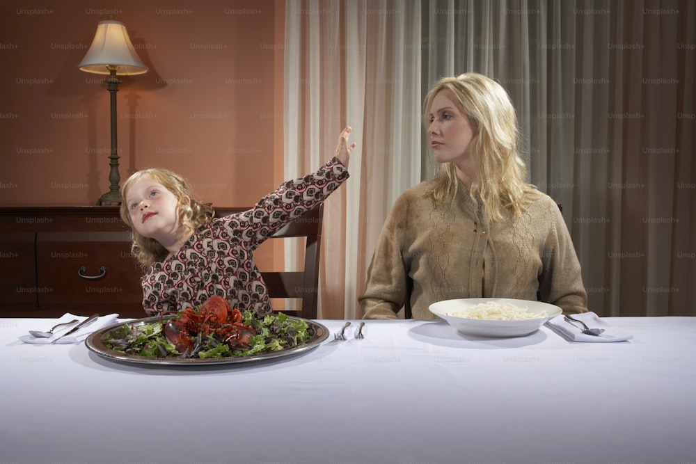 a woman and a child sitting at a table with a plate of food