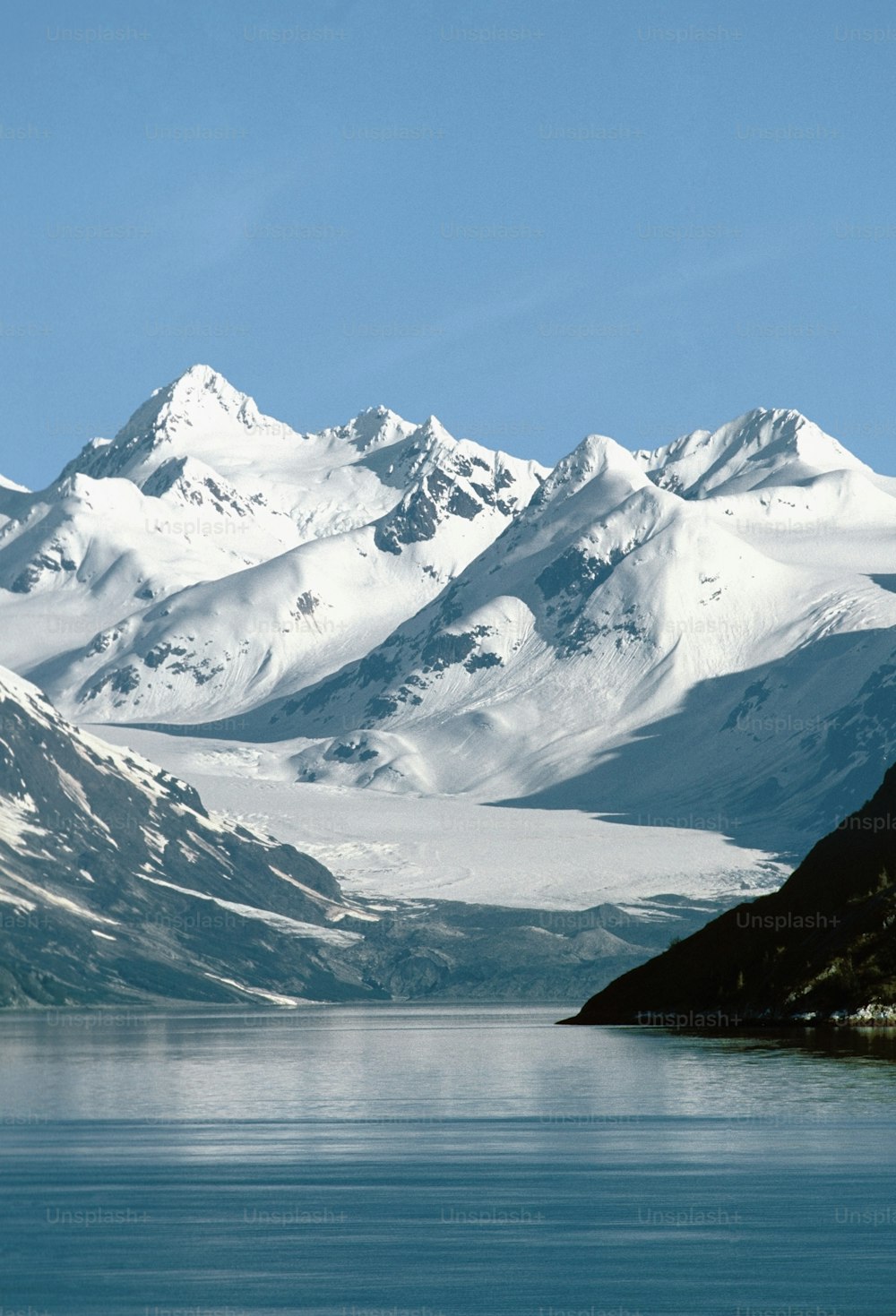eine schneebedeckte Bergkette neben einem Gewässer
