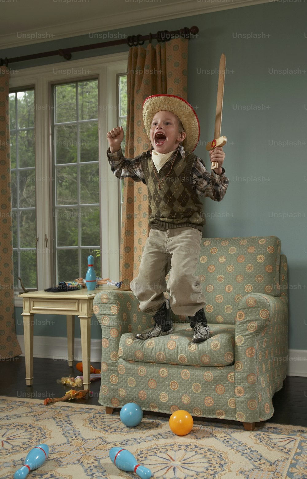 a little boy in a cowboy hat jumping on a couch