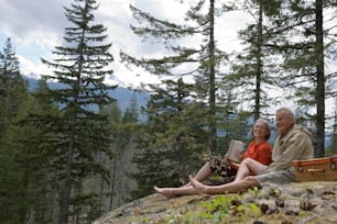 a man and a woman sitting on a rock in the woods