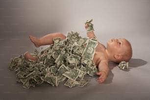 a baby laying on its back on a pile of money