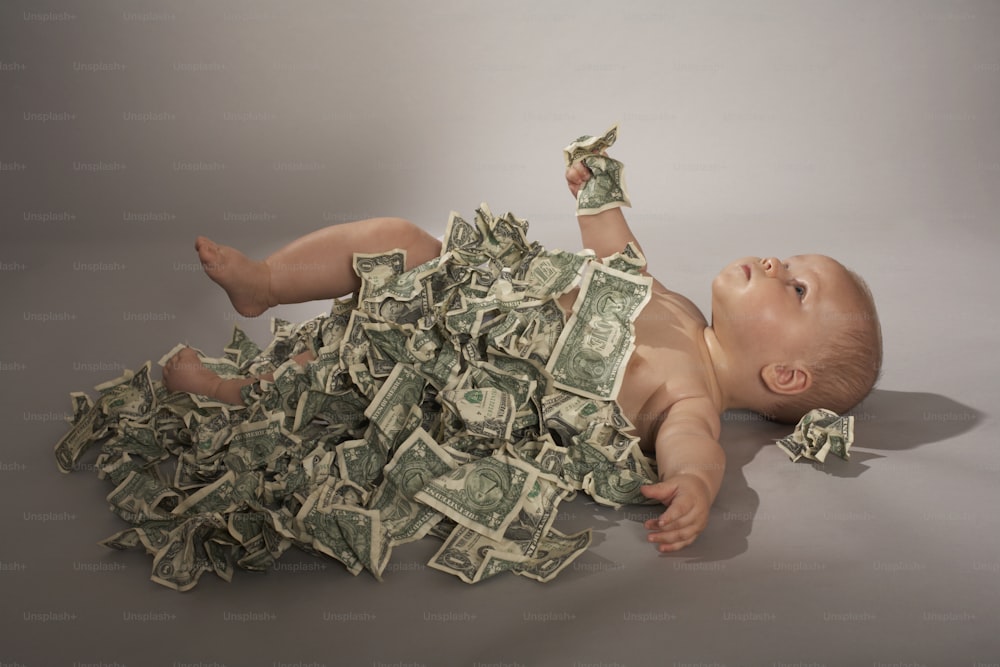 un bambino sdraiato sulla schiena su un mucchio di soldi
