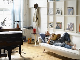 a man laying on a couch reading a book