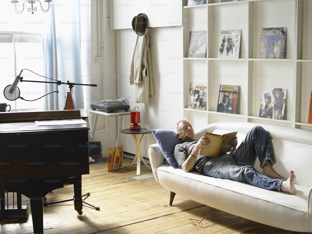 a man laying on a couch reading a book