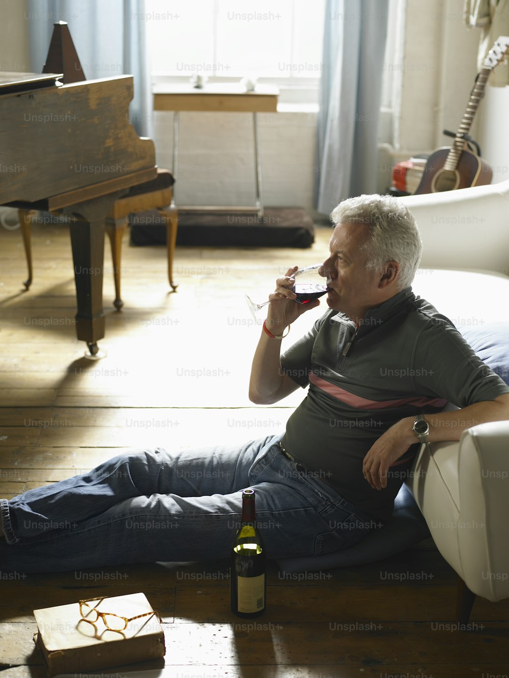 a man sitting on the floor drinking a glass of wine