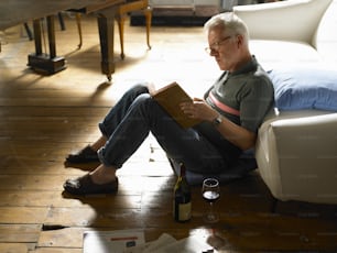 Un hombre sentado en el suelo leyendo un libro