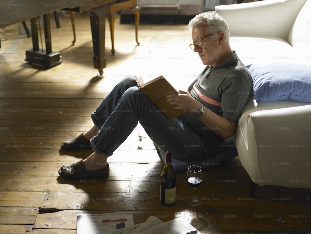 a man sitting on the floor reading a book