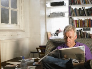 Un uomo seduto su un divano che legge un libro