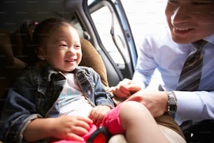 a little girl sitting in a car seat next to a man